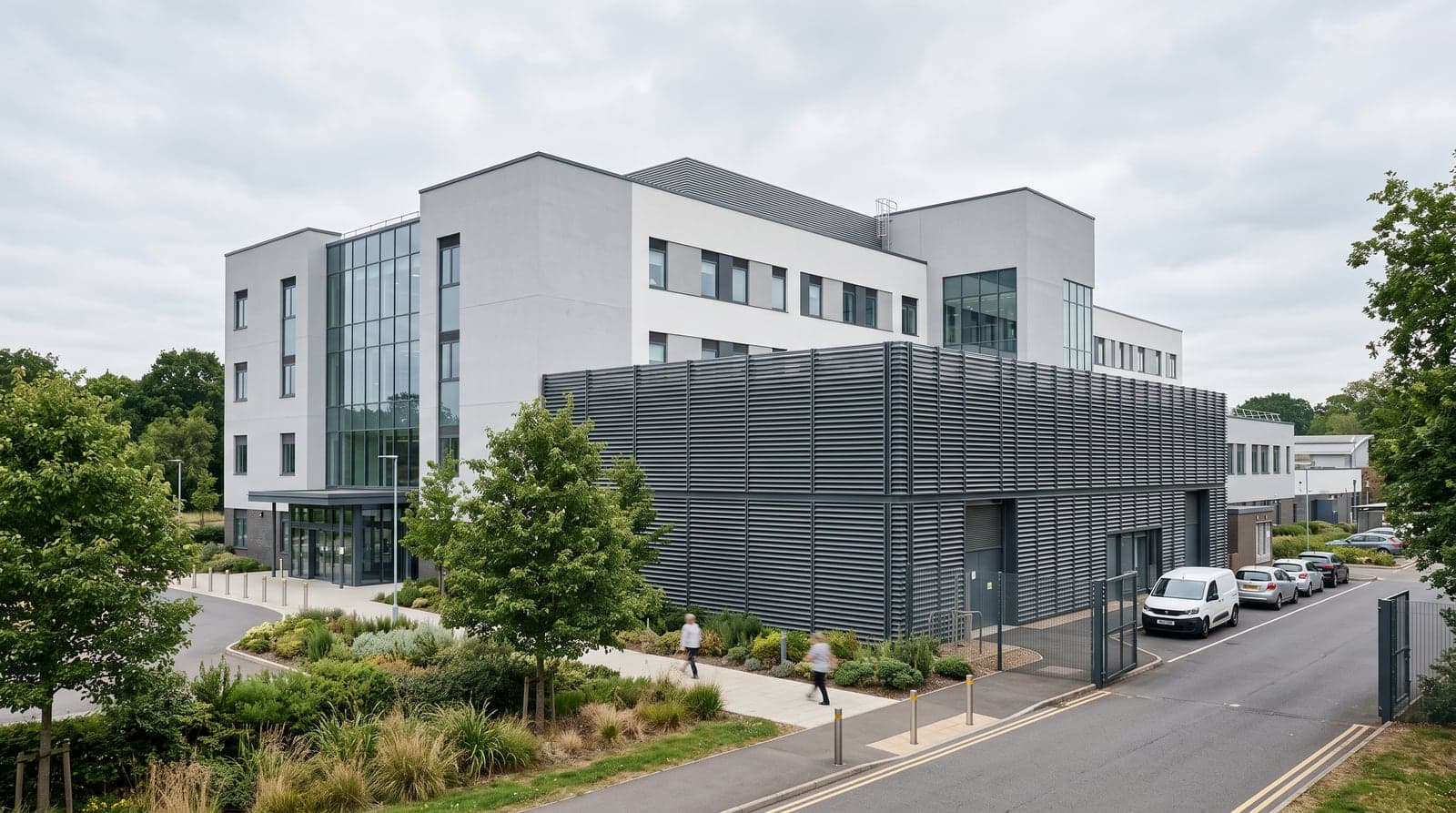 A modern hospital building with an external plant compound behind acoustic louvres