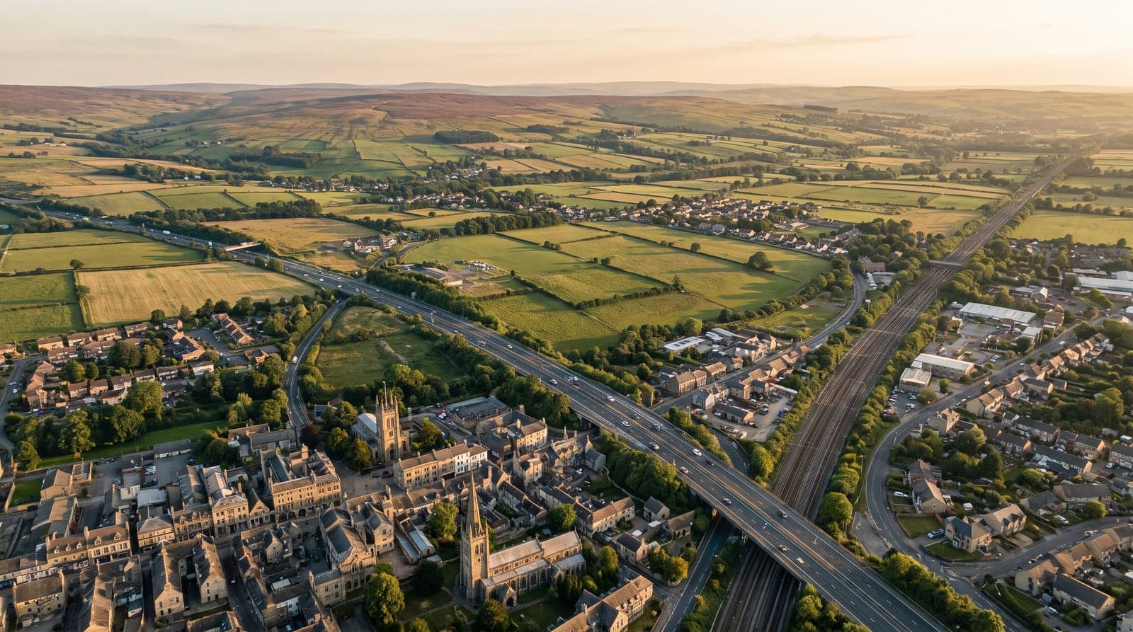 An aerial view over a British town, motorway, rail corridor and farmland